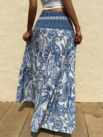 Person wearing a blue and white patterned skirt against a beige wall.
