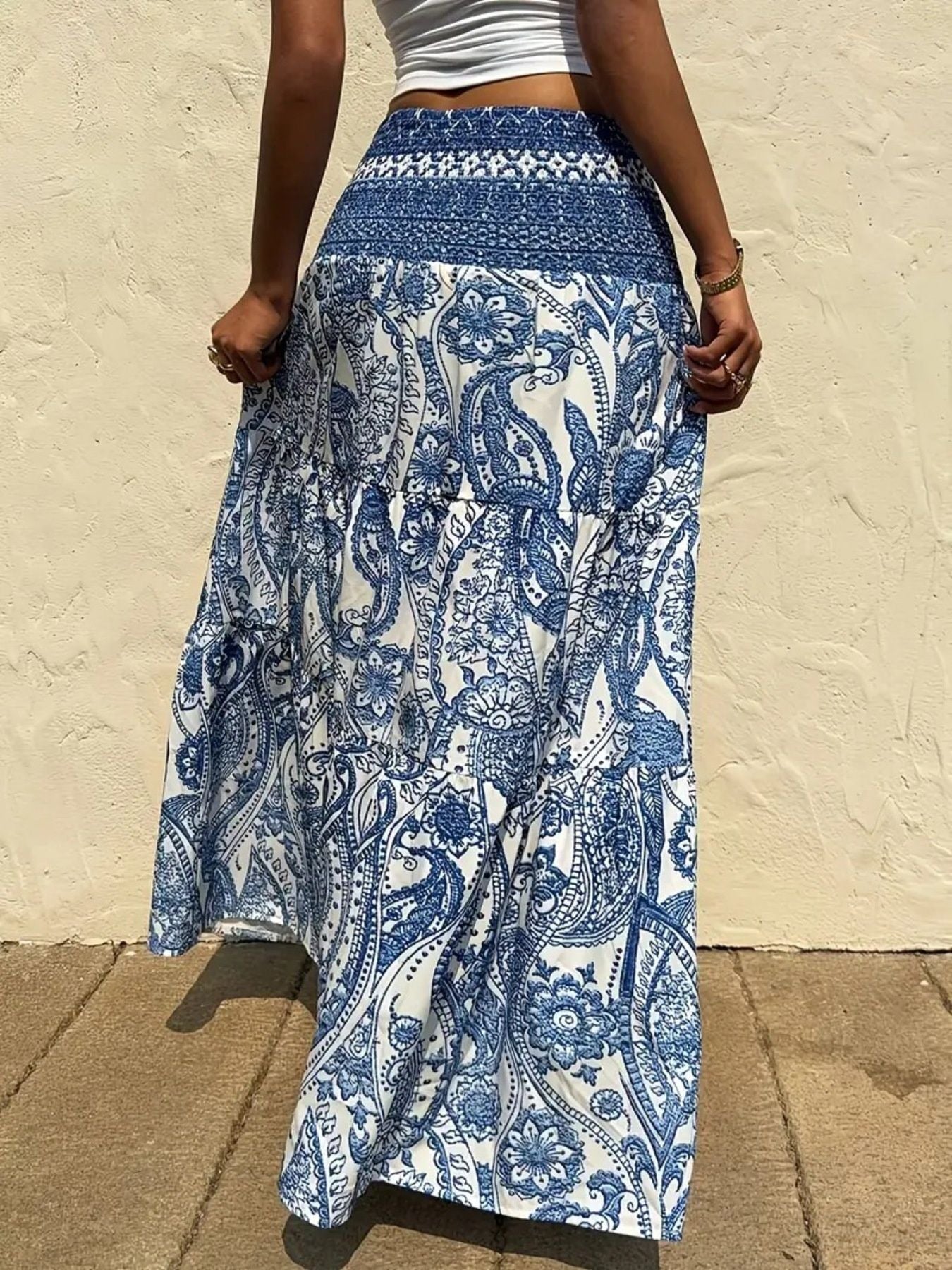 Person wearing a blue and white patterned skirt against a beige wall.