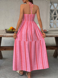 Woman wearing a pink patterned dress sitting on a wooden bench.