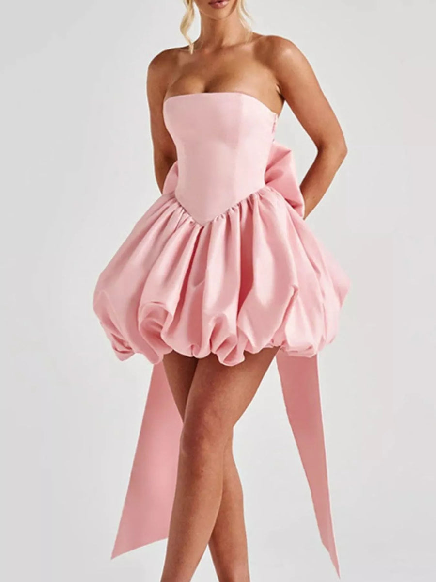Pink strapless dress with a ruffled skirt on a white background