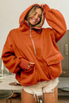 Person wearing a rust-colored hoodie in a kitchen setting