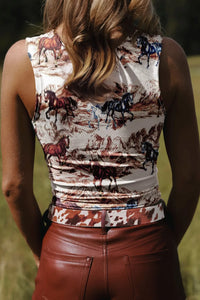 Person wearing a sleeveless top with horse print and brown leather pants in an outdoor setting