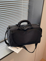 Black duffel bag on a surface with blinds in the background