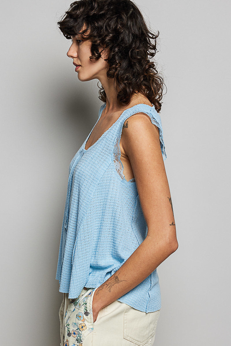 Woman wearing a light blue sleeveless top against a gray background