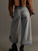 Person wearing wide-leg jeans from behind on a plain background