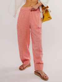 Person wearing pink checkered pants with a white background