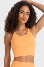 Woman wearing an orange sports bra and leggings on a white background