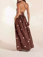 Brown dress with white polka dots worn by a model on a plain background