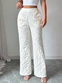 Person wearing textured white pants and a white top against a plain background