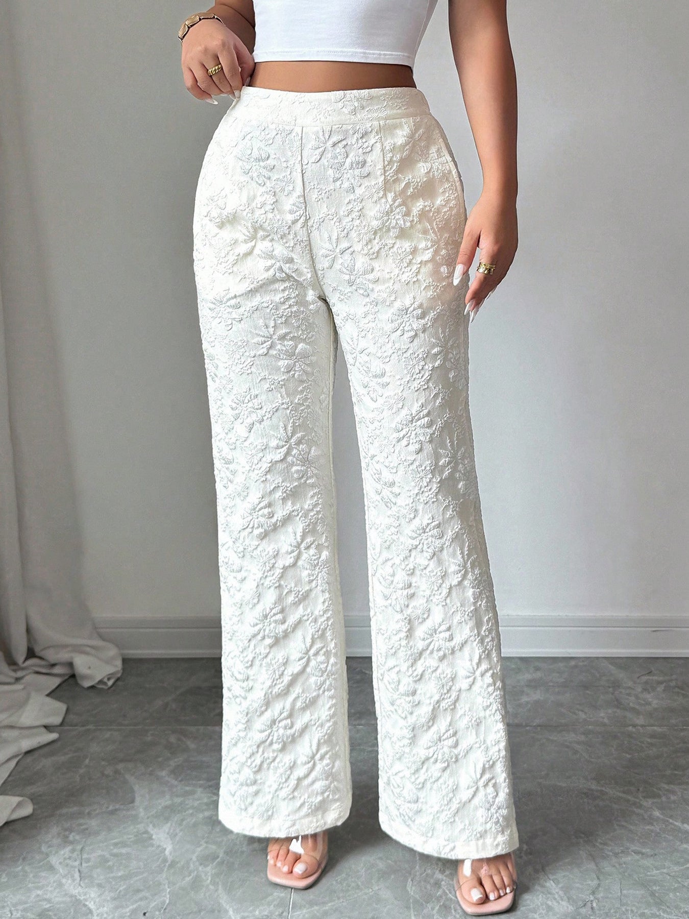 Person wearing textured white pants and a white top against a plain background