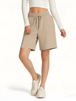 Person wearing beige shorts with a white top on a white background