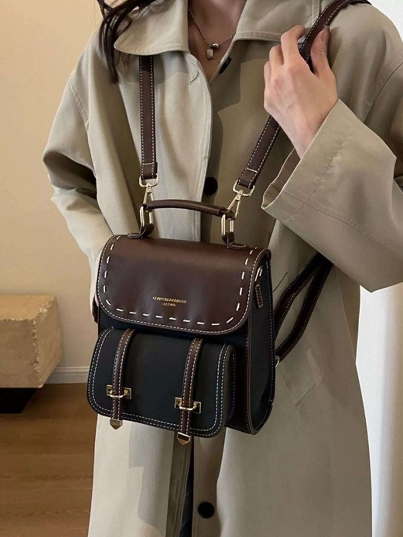 Person wearing a beige trench coat with a black and brown handbag.