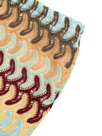 Close-up of a textured fabric with a pattern of wavy lines in brown, beige, and blue on a white background.