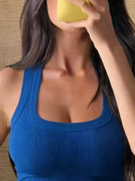 Person wearing a blue tank top with a yellow object in front of their face.