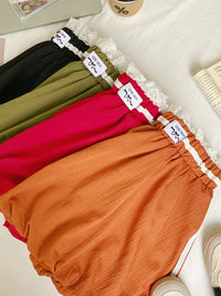 Four pairs of colorful bloomers with lace trim on a white surface.