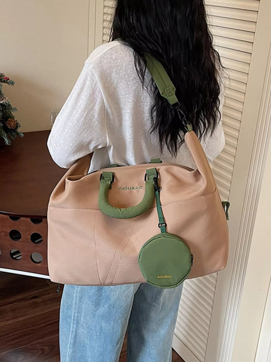 Person holding a beige handbag with green handles and accents indoors.