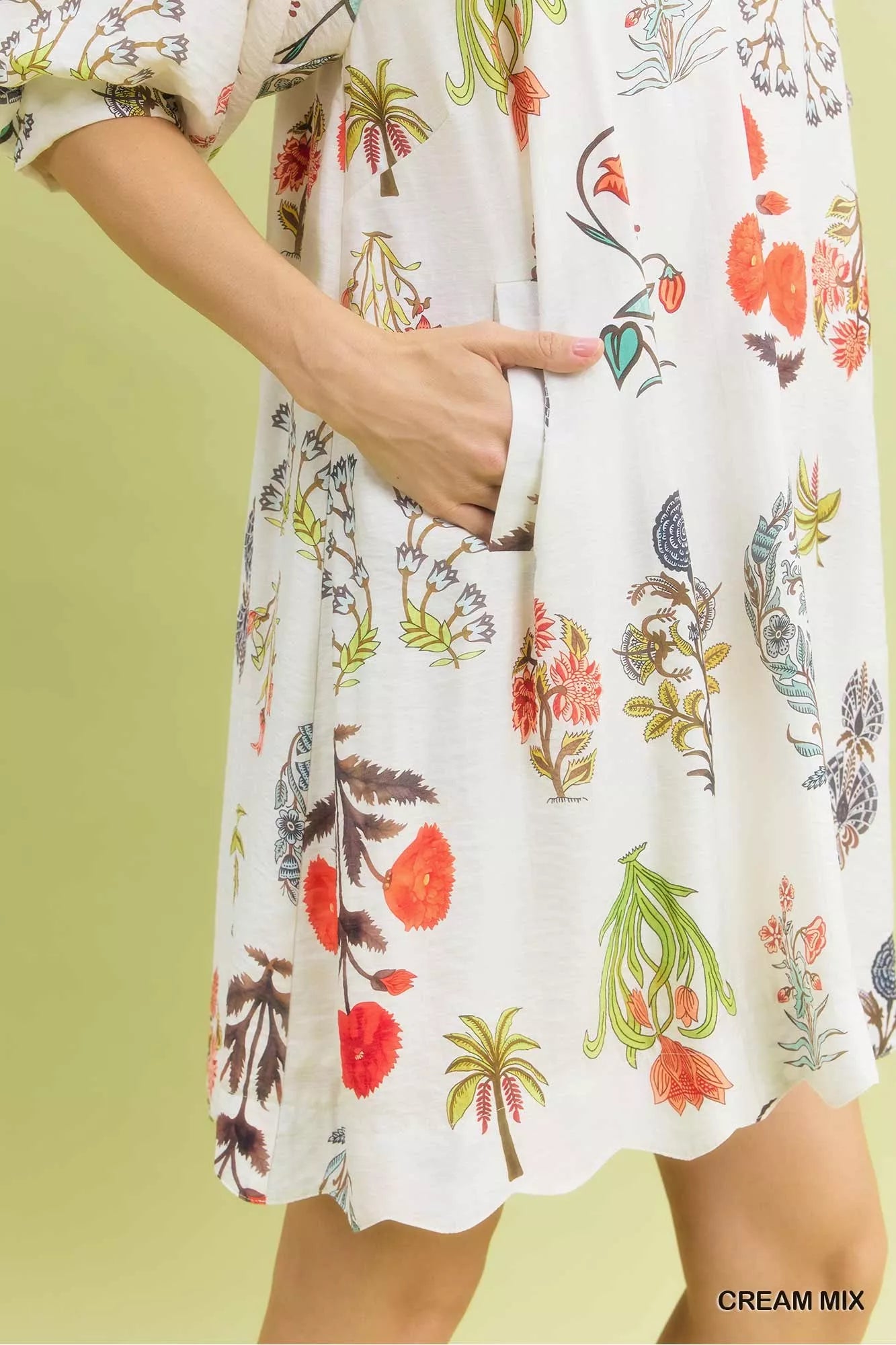 White dress with colorful floral and palm tree pattern on a green background