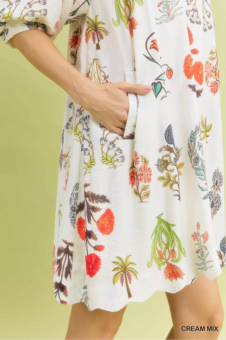 White dress with colorful floral and palm tree pattern on a green background
