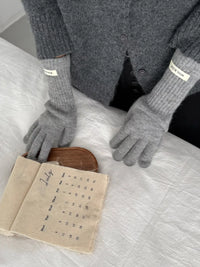 Person wearing gray gloves holding an open book on a light surface