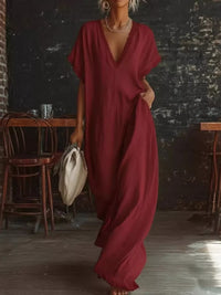 Person wearing a burgundy dress in an indoor setting with wooden furniture and a dark wall.