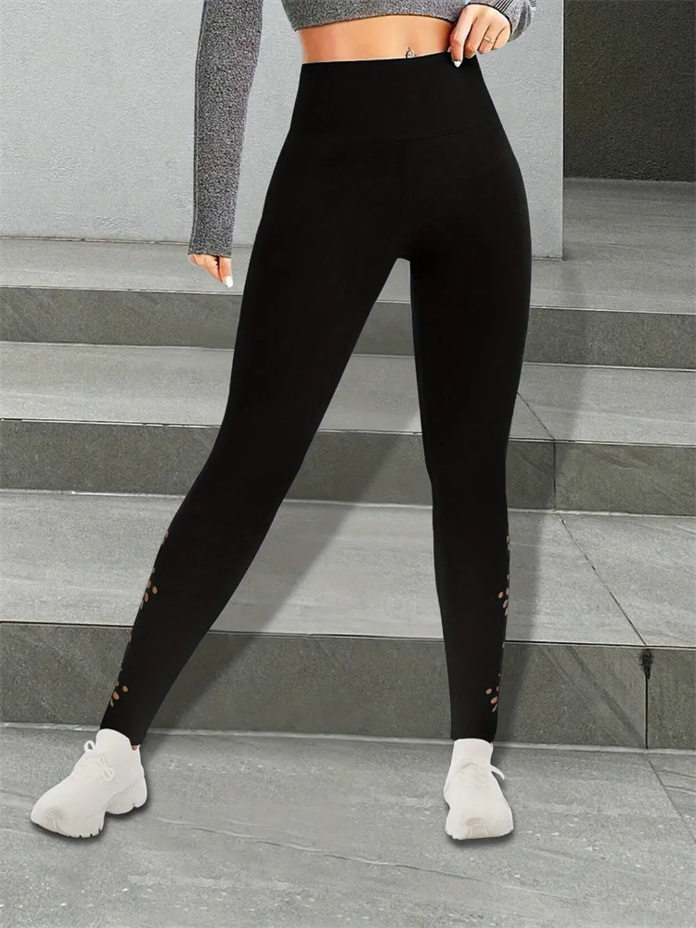 Person wearing black leggings with subtle designs on a gray stone staircase background
