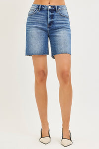 Denim shorts worn by a person on a plain background