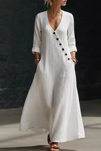 Woman wearing a white dress with black buttons against a dark background