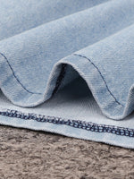 Close-up of blue denim fabric with visible stitching on a textured surface