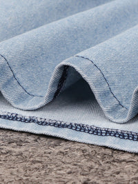 Close-up of blue denim fabric with visible stitching on a textured surface