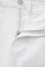 Close-up of a white denim zipper and button on a white background