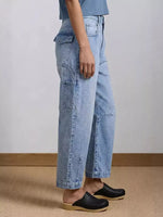 Person wearing light blue jeans and black clogs on a neutral background