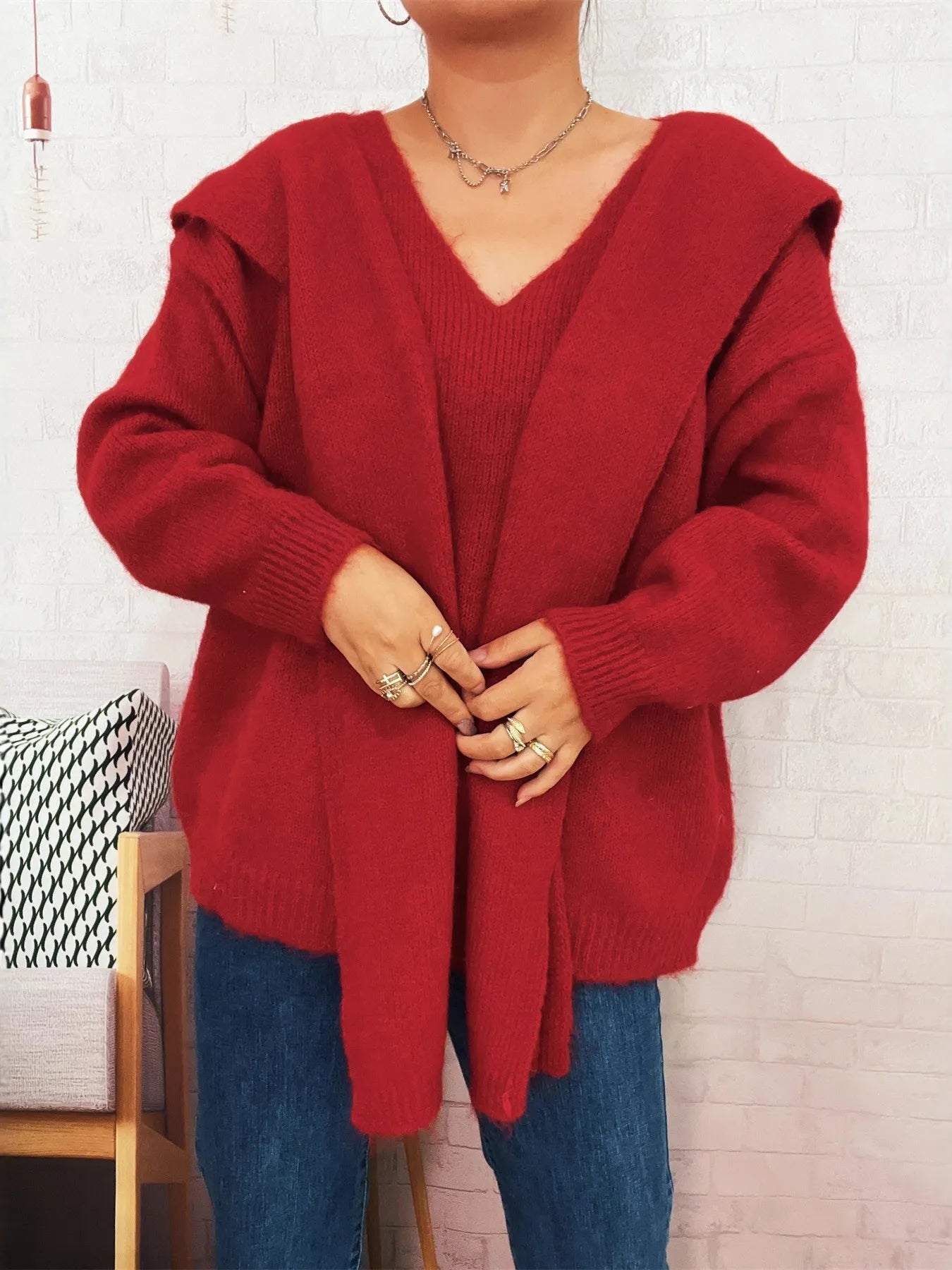 Person wearing a red hooded sweater against a white brick wall.