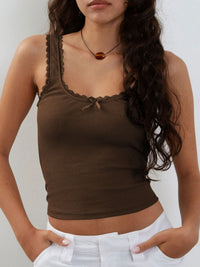 Woman wearing a brown ribbed tank top with lace details on a white background