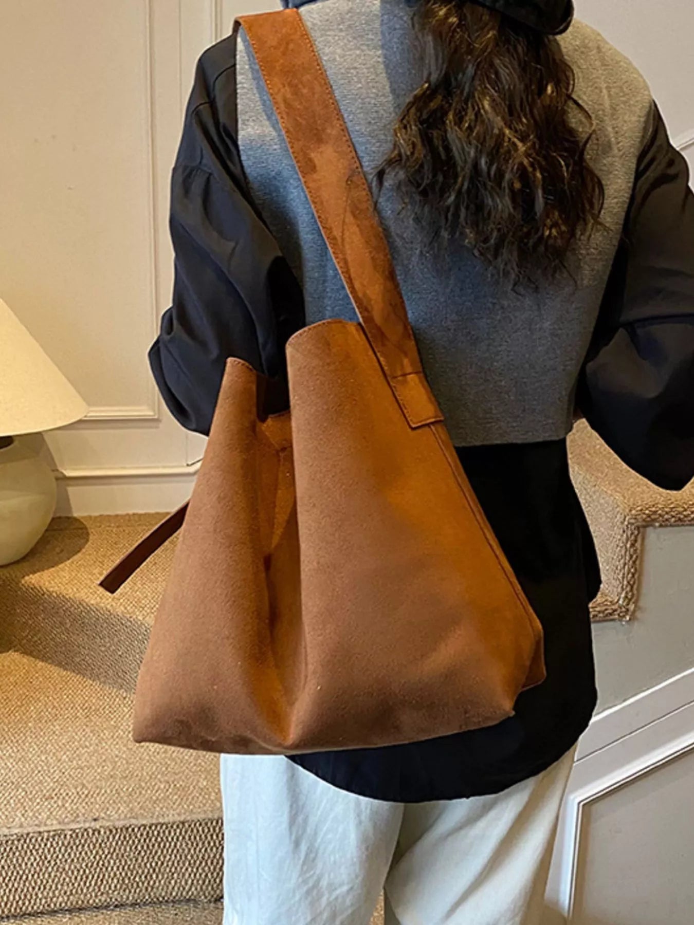 Person holding a brown leather bag indoors
