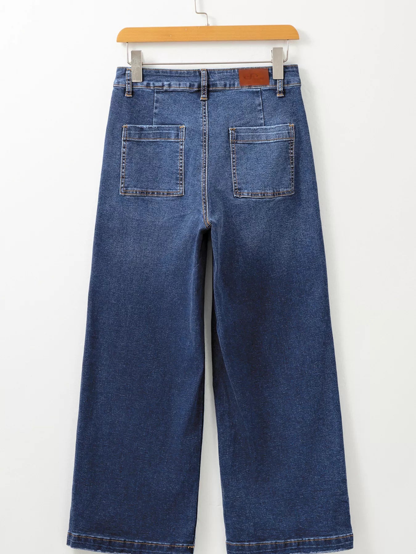Blue jeans on a hanger against a white background