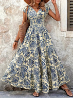 Woman wearing a floral dress standing against a stone wall.