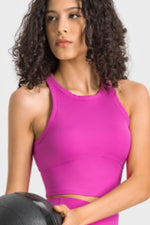 Woman wearing a pink sports bra holding a medicine ball against a plain background