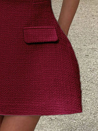 Close-up of a textured red dress with a pocket on a neutral background