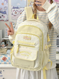 Person holding a light yellow backpack with 'Nudy' branding in a room with anime posters.