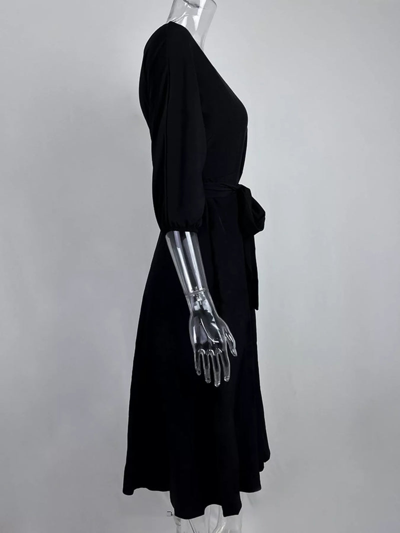 Mannequin wearing a black dress with a metallic arm on a gray background