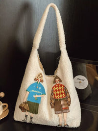 White textured bag with embroidered figures on a dark surface