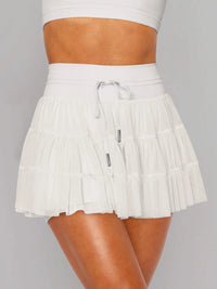 White pleated skirt worn by a person on a gray background