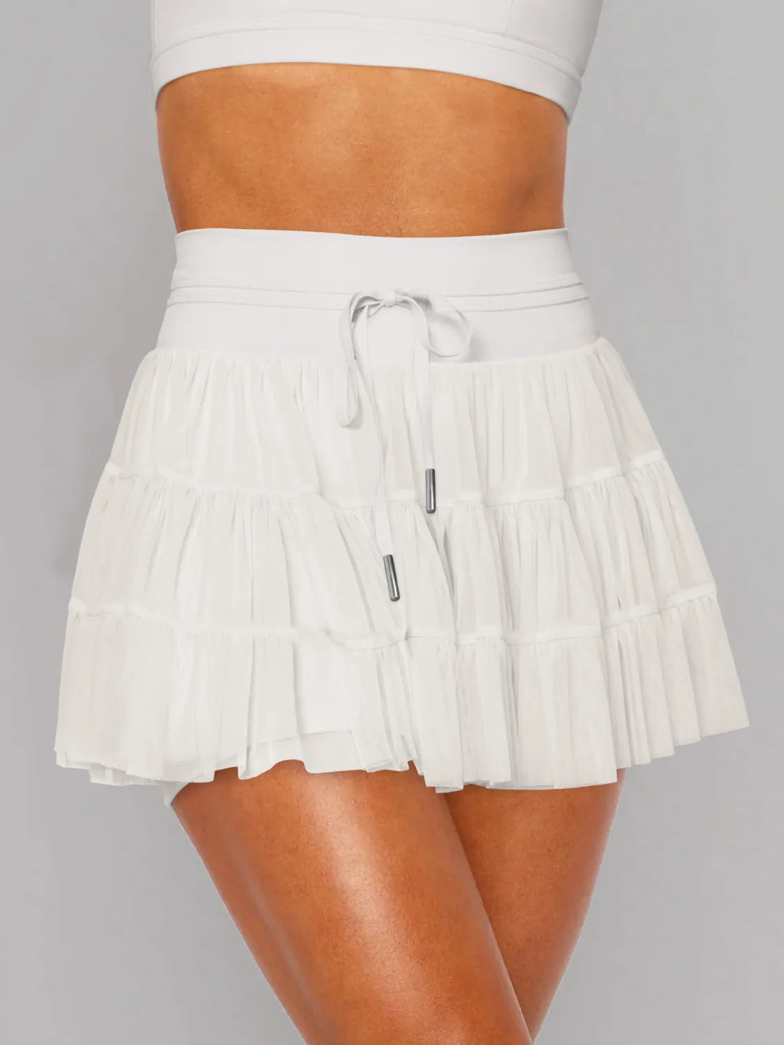 White pleated skirt worn by a person on a gray background