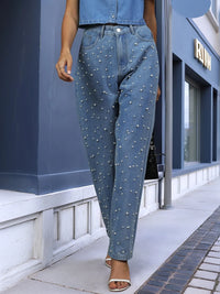 Person wearing blue jeans with rhinestone embellishments in an urban setting.