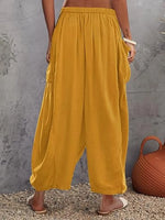 Mustard yellow wide-leg pants worn by a person against a gray wall.