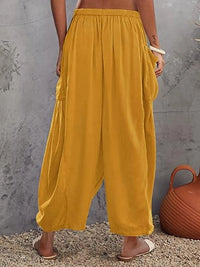 Mustard yellow wide-leg pants worn by a person against a gray wall.