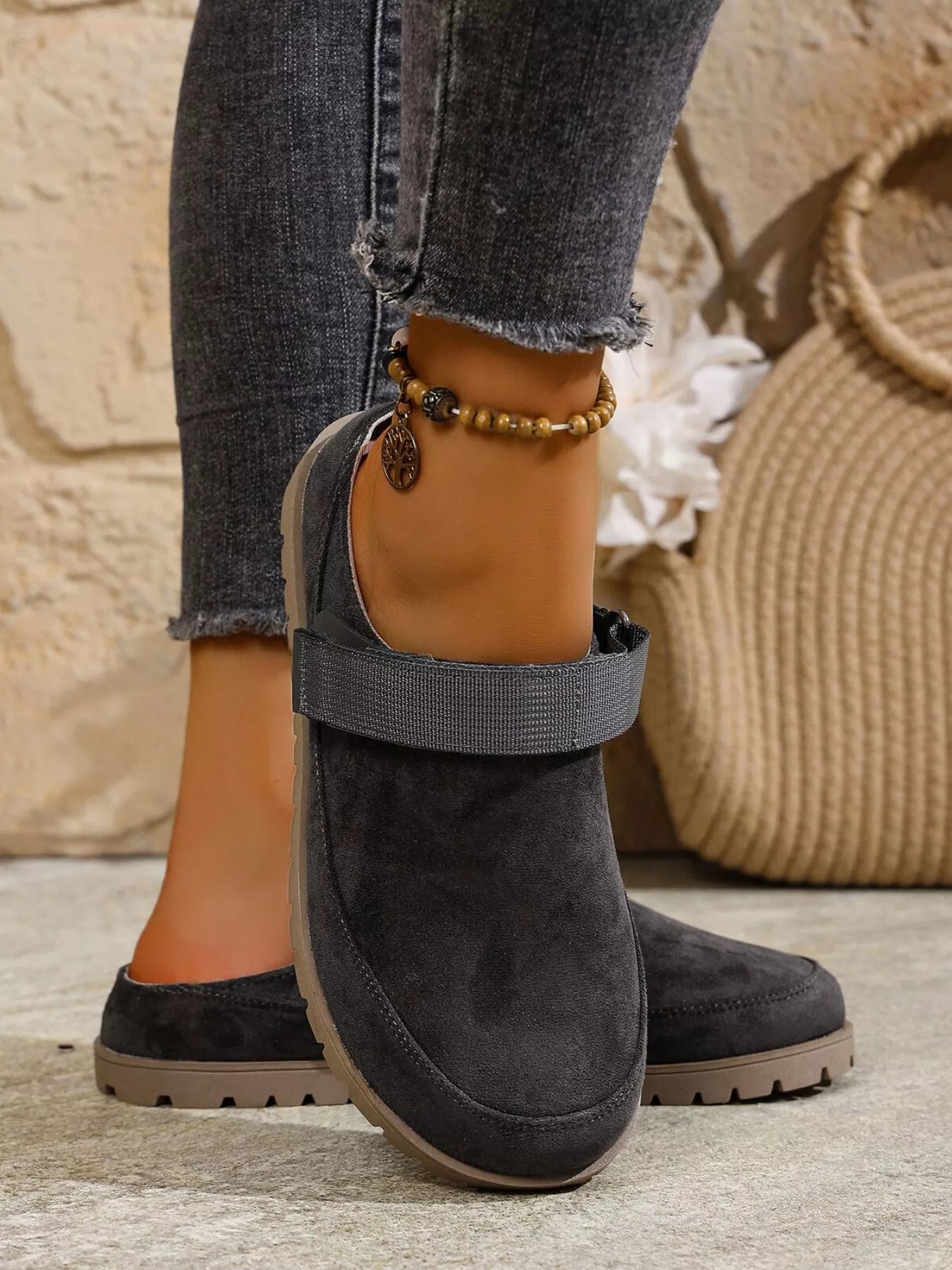 Dark gray ankle boots worn with rolled-up jeans on a neutral background