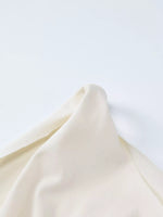 Close-up of a folded cream-colored fabric on a light gray background