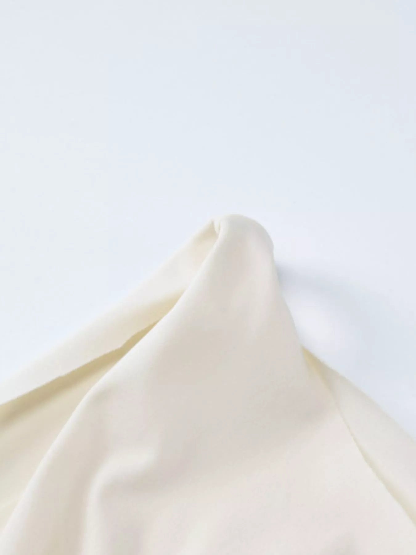 Close-up of a folded cream-colored fabric on a light gray background
