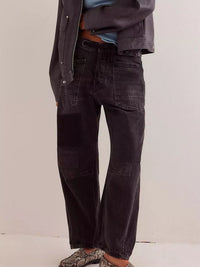 Person wearing black wide-leg jeans with a plain background